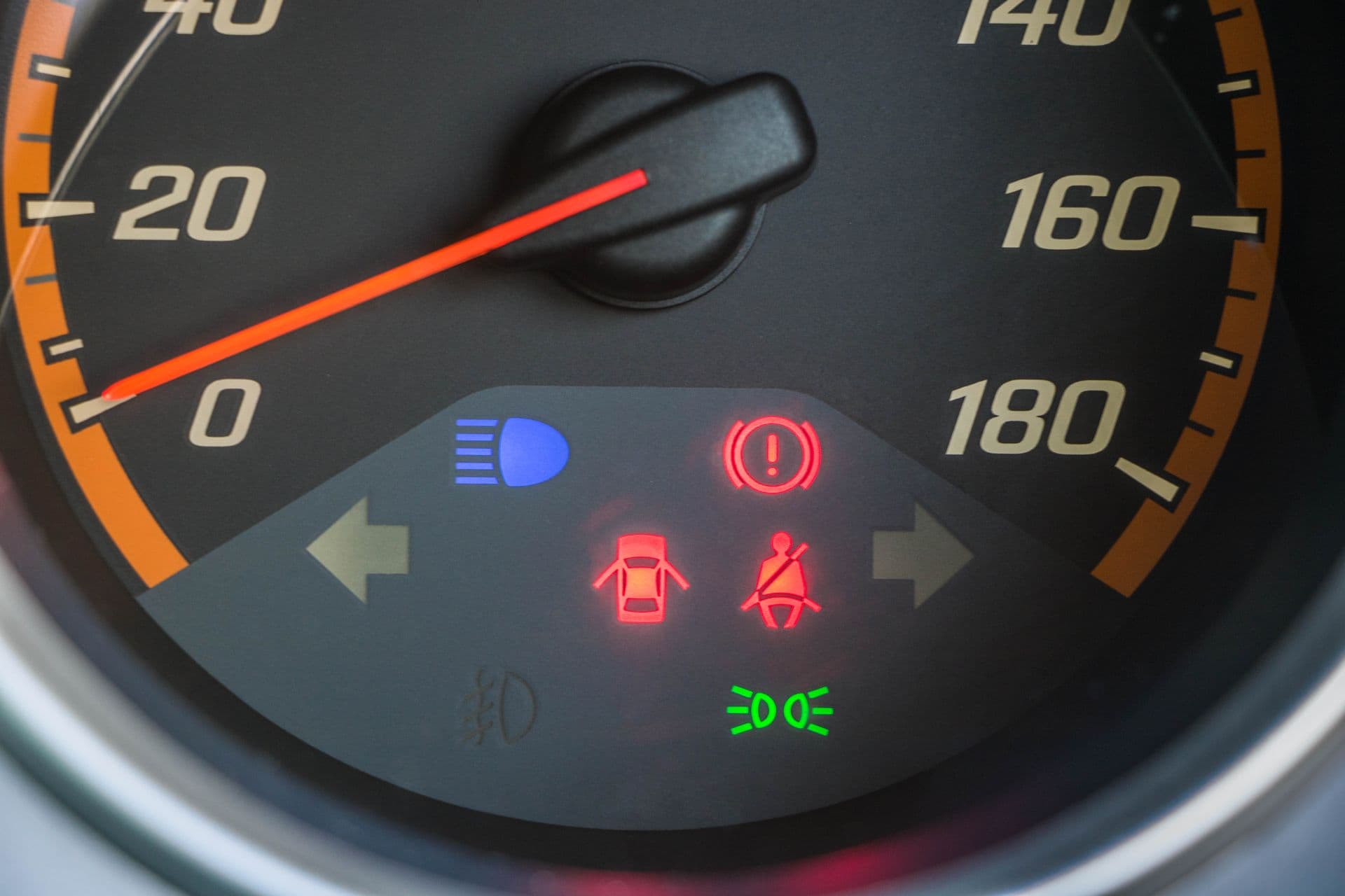 Battery and engine warning lights illuminated on a car dashboard beside the speedometer